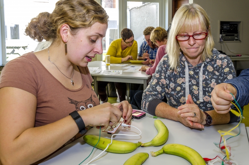 Twee deelnemers halen energie uit bananen tijdens activiteit